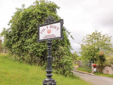 A signpost for Cil Y Bont Caravan and Motorhome Club near a country road with greenery