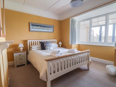 A bedroom with a double bed framed by two bedside tables and a large window at Tillicum in Charmouth