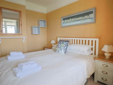 A bedroom with a bed with white linens and two bedside tables with lamps at Tillicum in Charmouth
