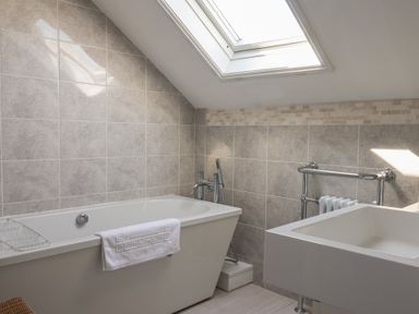 A bathroom with a bathtub a towel holder a sink under a skylight window at Tillicum in Charmouth