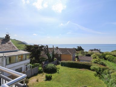 A garden with bushes and houses overlooking the sea at Tillicum in Charmouth