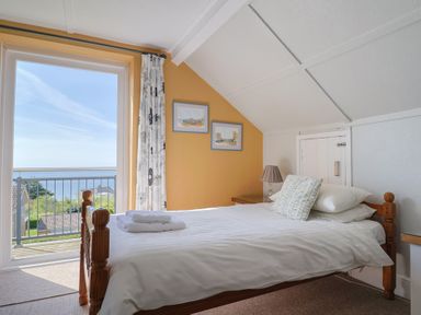 A bedroom with a single bed next to a window with ocean view at Tillicum in Charmouth