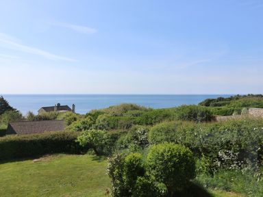 A garden with bushes and trees overlooking the sea at Tillicum in Charmouth