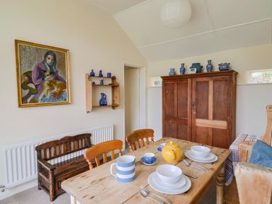 A dining room with a table set for tea at Penny Plot Cottage in Lyme Regis