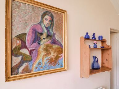 A painting and shelf with blue vases in a living room at Penny Plot Cottage in Lyme Regis