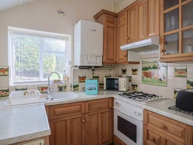 A kitchen with a sink, microwave, and gas stove at Penny Plot Cottage in Lyme Regis
