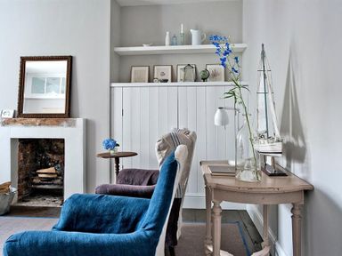 A sitting room with armchairs a fireplace a wooden table with a glass vase and a model sailboat at The Arched House in Lyme Regis