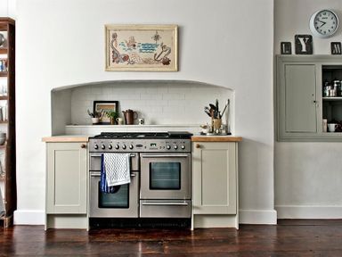 A kitchen with a stainless steel stove wooden floor and utensils on the counter at The Arched House in Lyme Regis