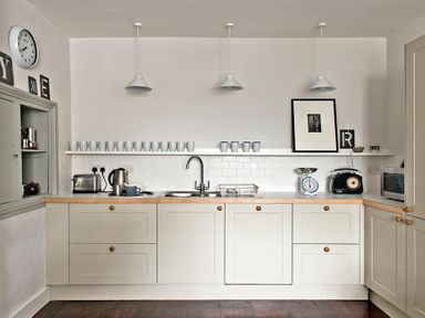 A kitchen with cupboards sink toaster kettle and cups on a shelf at The Arched House in Lyme Regis