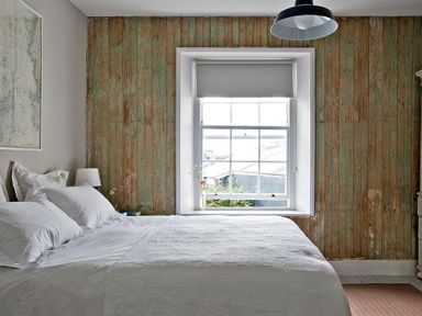 A bedroom with a large bed white bedding a window with a blind and a wooden paneled wall at The Arched House in Lyme Regis