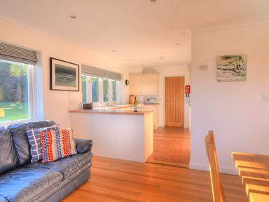 A kitchen area with wooden floor and a blue sofa with cushions at Pendower in Charmouth