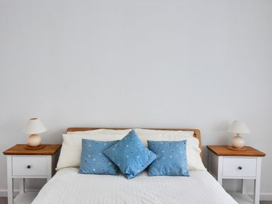 A bedroom with a bed with white bedding and blue pillows and two bedside tables with lamps at Pendower in Charmouth