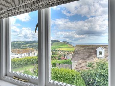 A view of houses bushes and distant hills from a window at Pendower in Charmouth