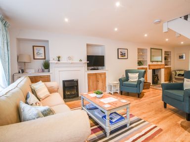 A living room with sofas armchairs a coffee table and a fireplace at Nutwood in Charmouth