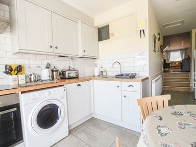 A kitchen with white cabinets washing machine toaster and a sink at Nutwood in Charmouth