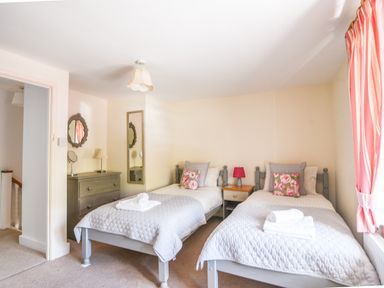 A bedroom with two single beds a chest of drawers and a bedside table at Nutwood in Charmouth