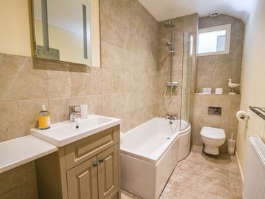 A bathroom with a bathtub shower toilet sink and mirror at Nutwood in Charmouth