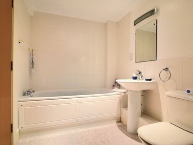 A bathroom with a bathtub sink mirror and toilet at 9 Maritime House in West Bay
