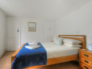A bedroom with a wooden bed with white pillows and a blue blanket and white towels on the bed at Monmouth Cottage in Lyme Regis