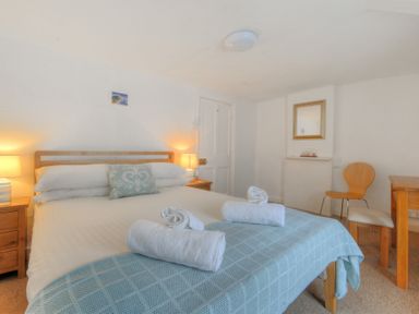 A bedroom with a double bed and rolled towels on the blanket at Monmouth Cottage in Lyme Regis