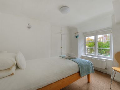 A bedroom with a single bed next to a window and a chair at Monmouth Cottage in Lyme Regis