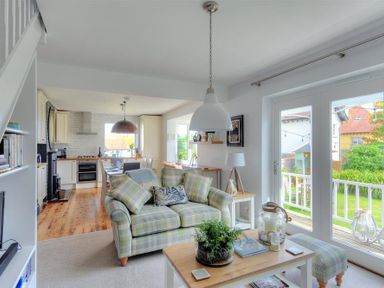 A living room with a sofa and coffee table next to large glass doors leading to a garden at Highpoint Lodge in Lyme Regis