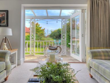 A living room with a wooden table plants and a lamp next to the door opening to a garden at Highpoint Lodge in Lyme Regis
