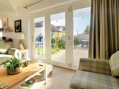 A living room with a plaid armchair coffee table and sliding glass doors opening to a garden at Highpoint Lodge in Lyme Regis