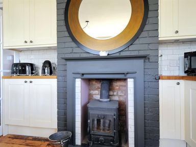 A kitchen with a black stove in a gray fireplace and white cabinets at Highpoint Lodge in Lyme Regis