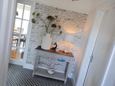 A hallway with a console table holding a vase with branches a lamp and decorative items at Highpoint Lodge in Lyme Regis