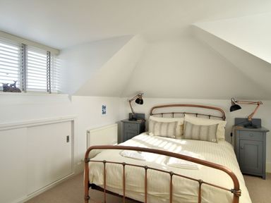 A bedroom with a metal bed frame two bedside tables with lamps and a window with blinds at Highpoint Lodge in Lyme Regis