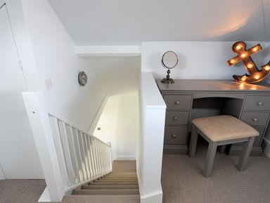 A staircase next to a gray desk with a stool a small mirror and an illuminated anchor decoration at Highpoint Lodge in Lyme Regis