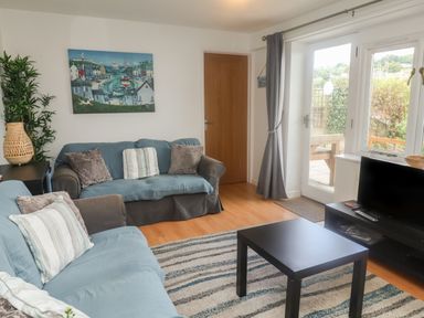 A living room with two sofas a coffee table a television and a large window at Bay View in Lyme Regis