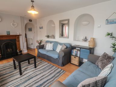 A living room with two sofas a black coffee table a fireplace and shelves at Bay View in Lyme Regis