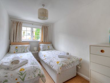 A bedroom with two single beds with floral bedding and a small white chest of drawers at Bay View in Lyme Regis