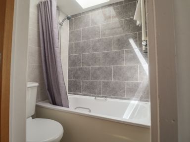 A bathroom with a bathtub shower curtain and toilet at Bay View in Lyme Regis