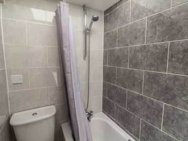 A bathroom with a bathtub shower combination and toilet at Bay View in Lyme Regis