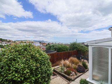 A garden with shrubs a seating area a wooden fence and houses in the distance at Bay View in Lyme Regis