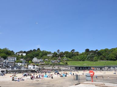 A beach with people on sand and houses on a hill behind at Cleve Cottage in Lyme Regis
