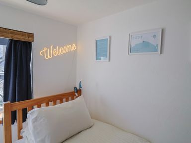 A bedroom with a bed and welcome sign at Cleve Cottage in Lyme Regis