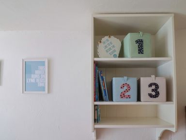 A shelf with storage boxes and books at Cleve Cottage in Lyme Regis