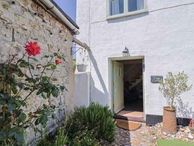 An entrance with a flower and stone wall at Cleve Cottage in Lyme Regis