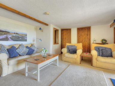 A living room with sofas cushions a coffee table and wooden doors at Willows in Charmouth