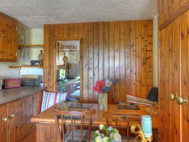 A wooden dining area with a table and chairs a vase with flowers and striped cushions at Willows in Charmouth