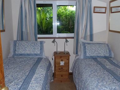 A bedroom with two single beds and a wooden nightstand with lamps at Willows in Charmouth