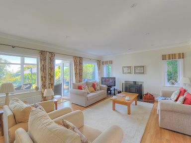 A living room with beige sofas a wooden coffee table and a fireplace at Somerhill in Lyme Regis
