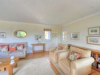 A sitting room with sofas armchairs wooden table and framed pictures on the walls at Somerhill Lyme Regis