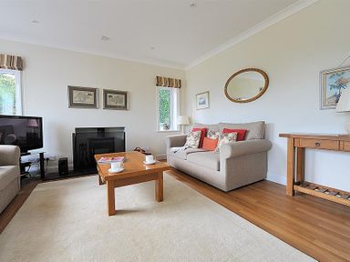 A living room with two beige sofas a wooden coffee table and a television at Somerhill in Lyme Regis