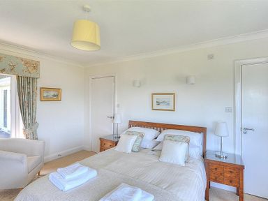 A bedroom with a double bed two bedside tables lamps an armchair and floral curtains at Somerhill in Lyme Regis