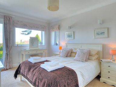 A bedroom with a bed linens bedside tables dressing table and framed pictures at Somerhill Lyme Regis